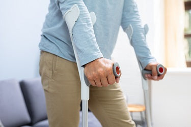 Adult using forearm crutches with forearm cuff and handgrip during injury recovery