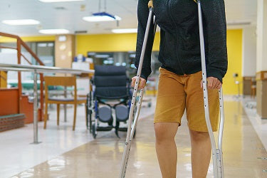 Adult walking with adjustable underarm crutches during temporary injury recovery